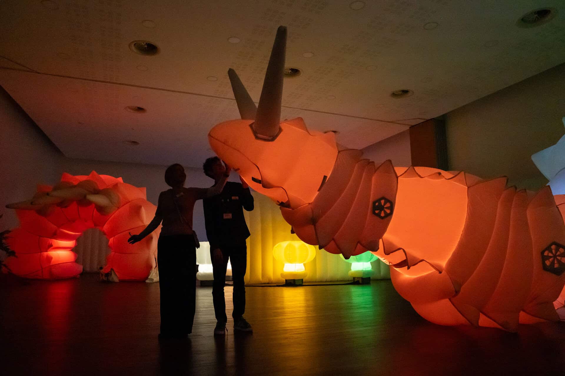 Adults stood in front of Luma - a giant, glowing robotic snail