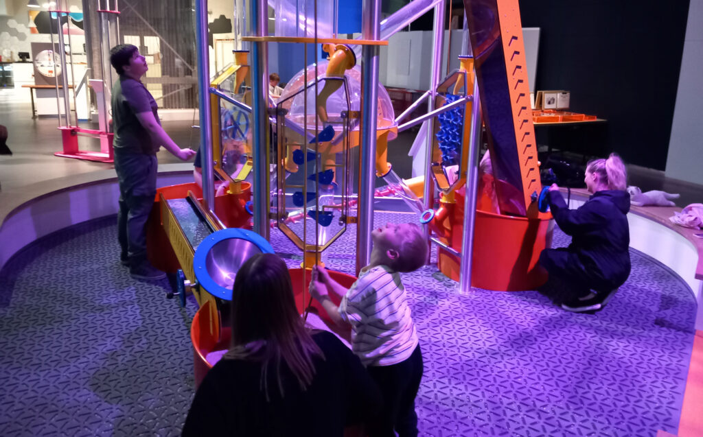 North East Autism Society family gathered around exhibit in Wow Zone.