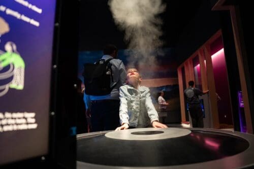 Child enjoying smoke ring activity in Life Science Centre's Lightbox exhibition.