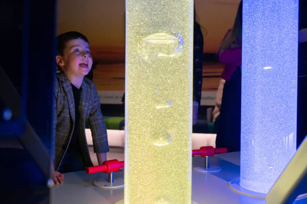 Young boy looking a tubes filled with colourful liquid in Life Science Centre's Lightbox