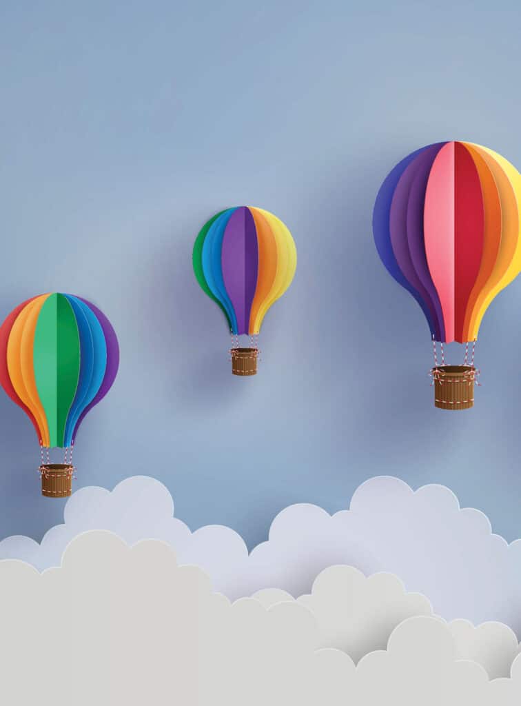 5 rainbow coloured paper hot air balloons floating in the clouds