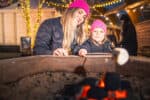 Mother and daughter toasting marshmallows on ourdoor firepit at Life Science Centre ice rink.
