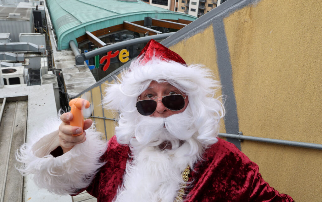 Santa using a fan and wearing sunglasses on Life Science Centre roof.