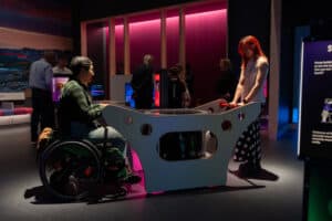 Two young adults using the heartbeat drum and facing one another in Life Science Centre's Lightbox exhibition.