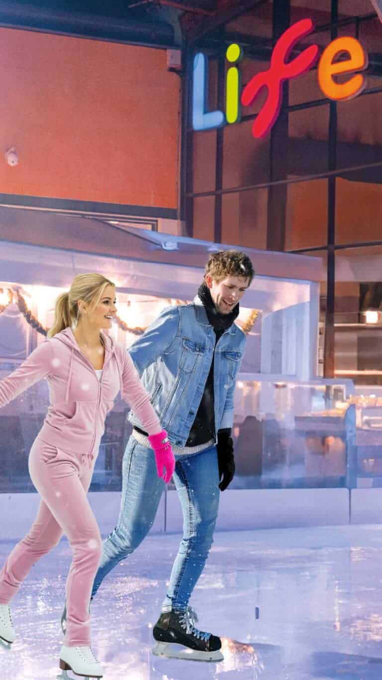 Couple dressed in noughties inspired clothing on Life Science Centre ice rink in Newcastle. The woman is wearing a pink tracksuit whilst the man is in double denim.