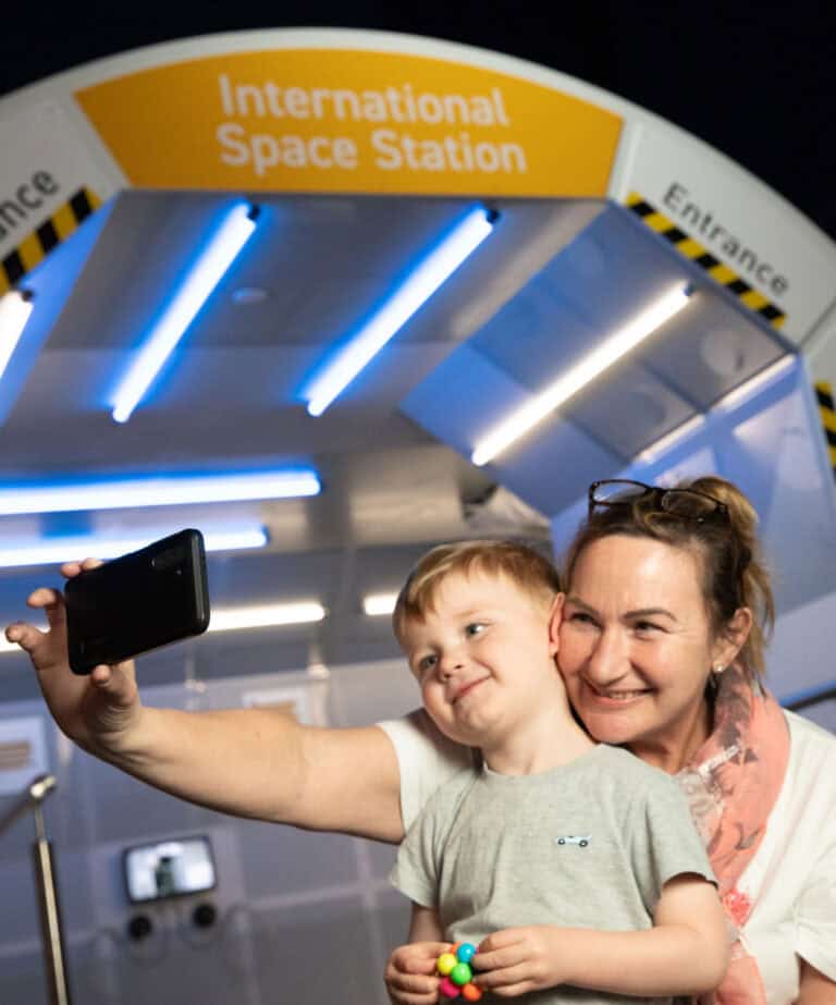Grandma And Child In Life Science Centre's Space Zone Taking A Selfie In Front Of The Model International Space Station