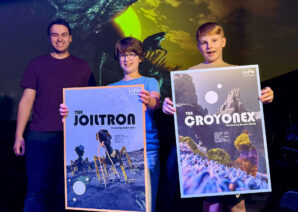 Sophie Harris and Harrison Hardy holding posters of their aliens in Life Science Centre's Planetarium.