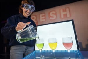Explainer in Life Science Centre's Theatre doing an experiment with brightly coloured liquids.