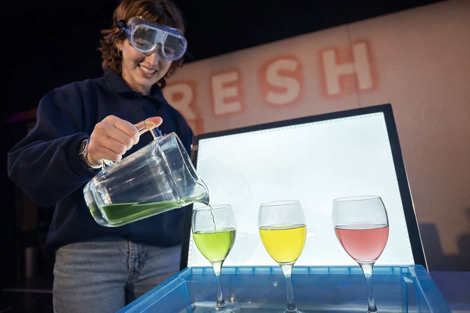 Explainer in Life Science Centre's Theatre doing an experiment with brightly coloured liquids.