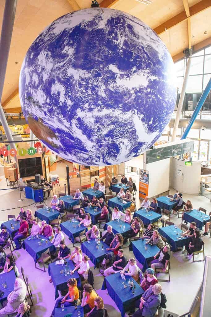 Adults on tables under Gaia, our replica of Planet Earth. 