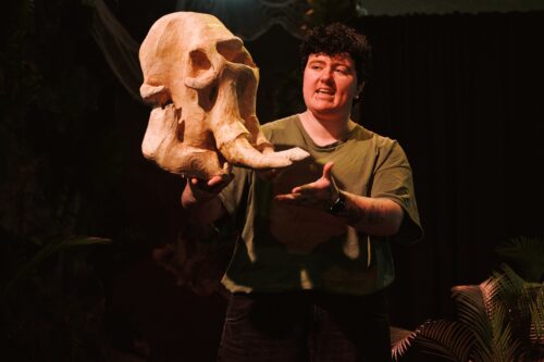 Life Science Explainer holding a dinosaur fossil in live science show.