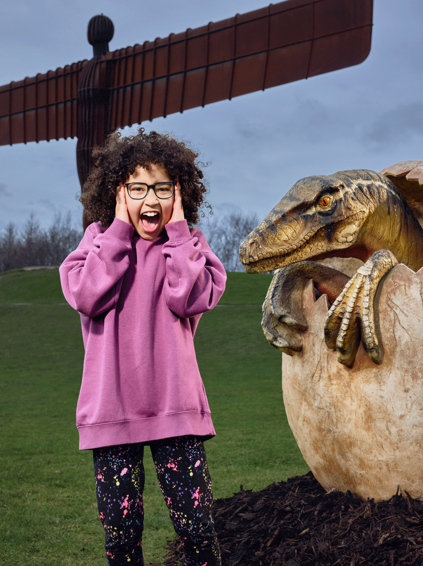 Little girl in front of Angel of the North next to dino egg.