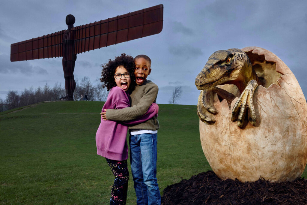 Two children stood in front of dinosaur egg at Angel of the North
