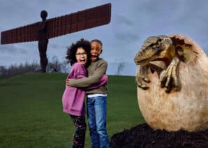 Two children stood in front of dinosaur egg at Angel of the North