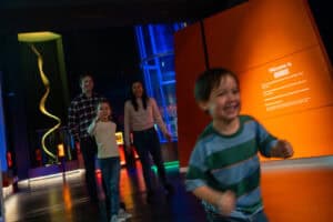 A family running out of Life's Lightbox exhibition, happy and smiling after their visit. The little boy runs ahead.