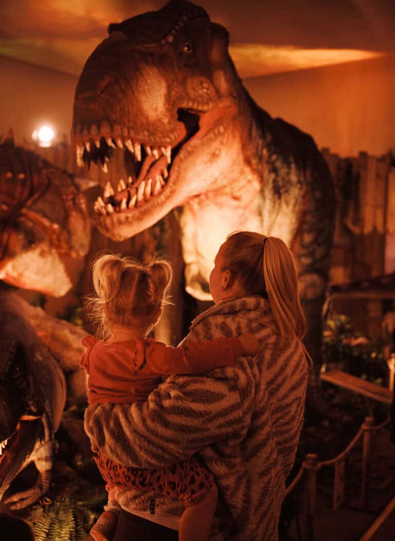 Mother and toddler looking at huge model of a T. rex dinosaur