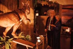 Two adults taking a photograph of a moving, animatronic dinosaur at Newcastle's Life Science Centre.