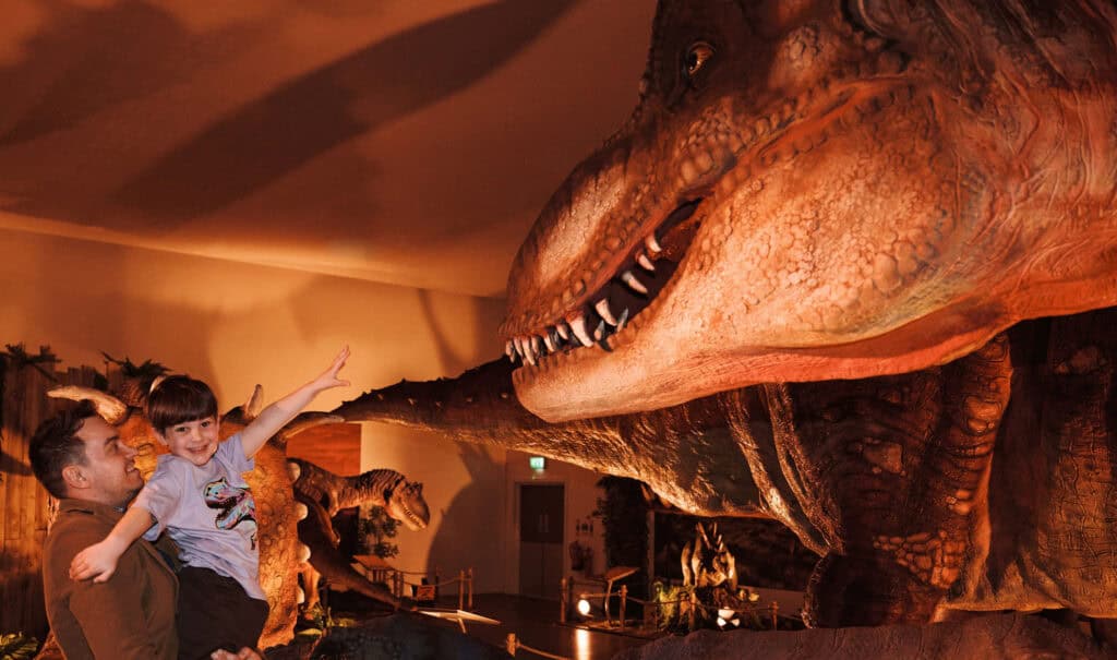 Dad holding a little boy in dinosaur exhibit at Newcastle's Life Science Centree
