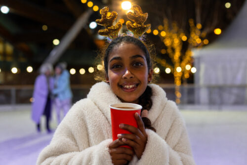 Little girl wearing a dressing gown and holding a hot chocolate on Newcastle's outdoor ice rink.
