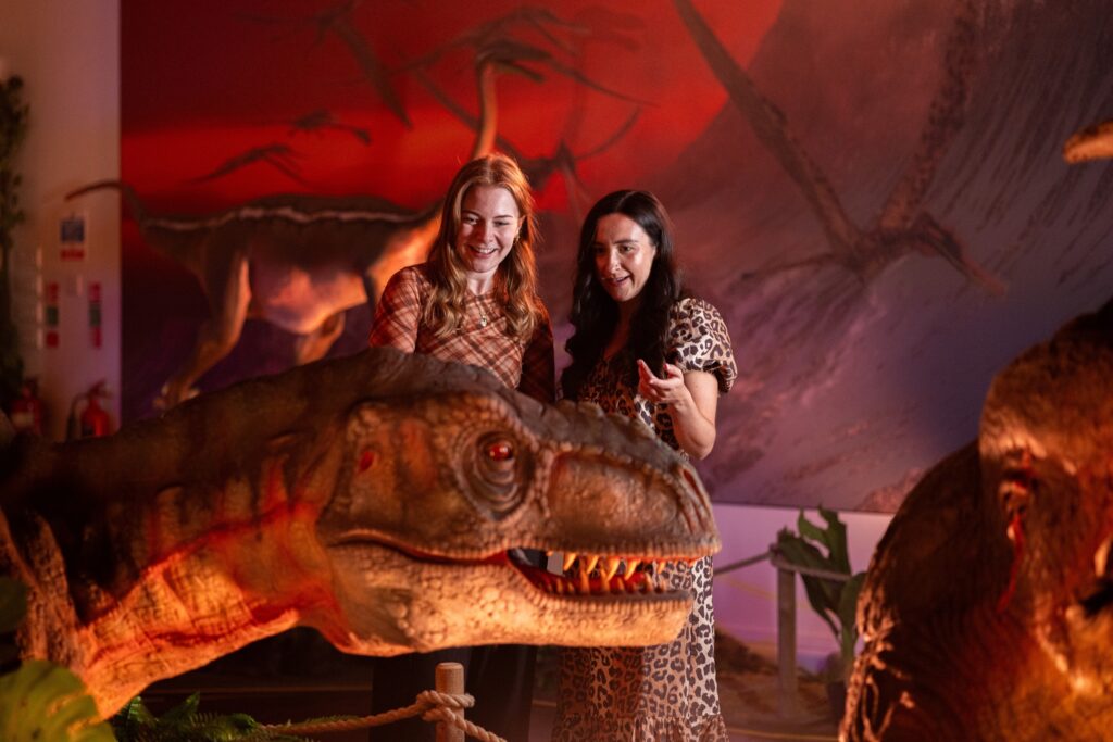 Two women in Newcastle's Life Science Centre looking at an animatronic T.rex