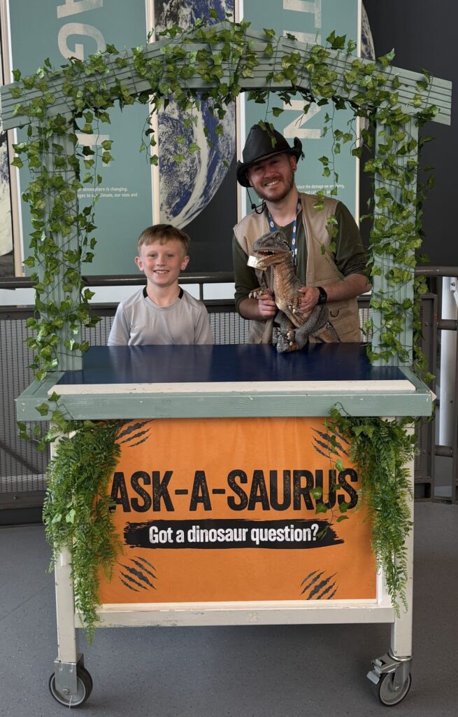Dino Ranger Jake pictured with young boy in front of a stand titled 'Ask-A-Saurus'