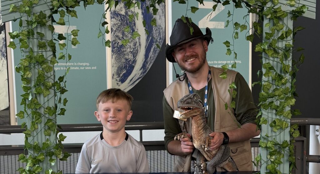 Dino Ranger Jake pictured with young boy in front of a stand titled 'Ask-A-Saurus'