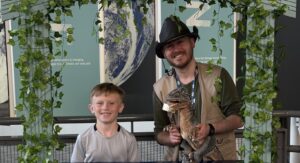 Dino Ranger Jake pictured with young boy in front of a stand titled 'Ask-A-Saurus'